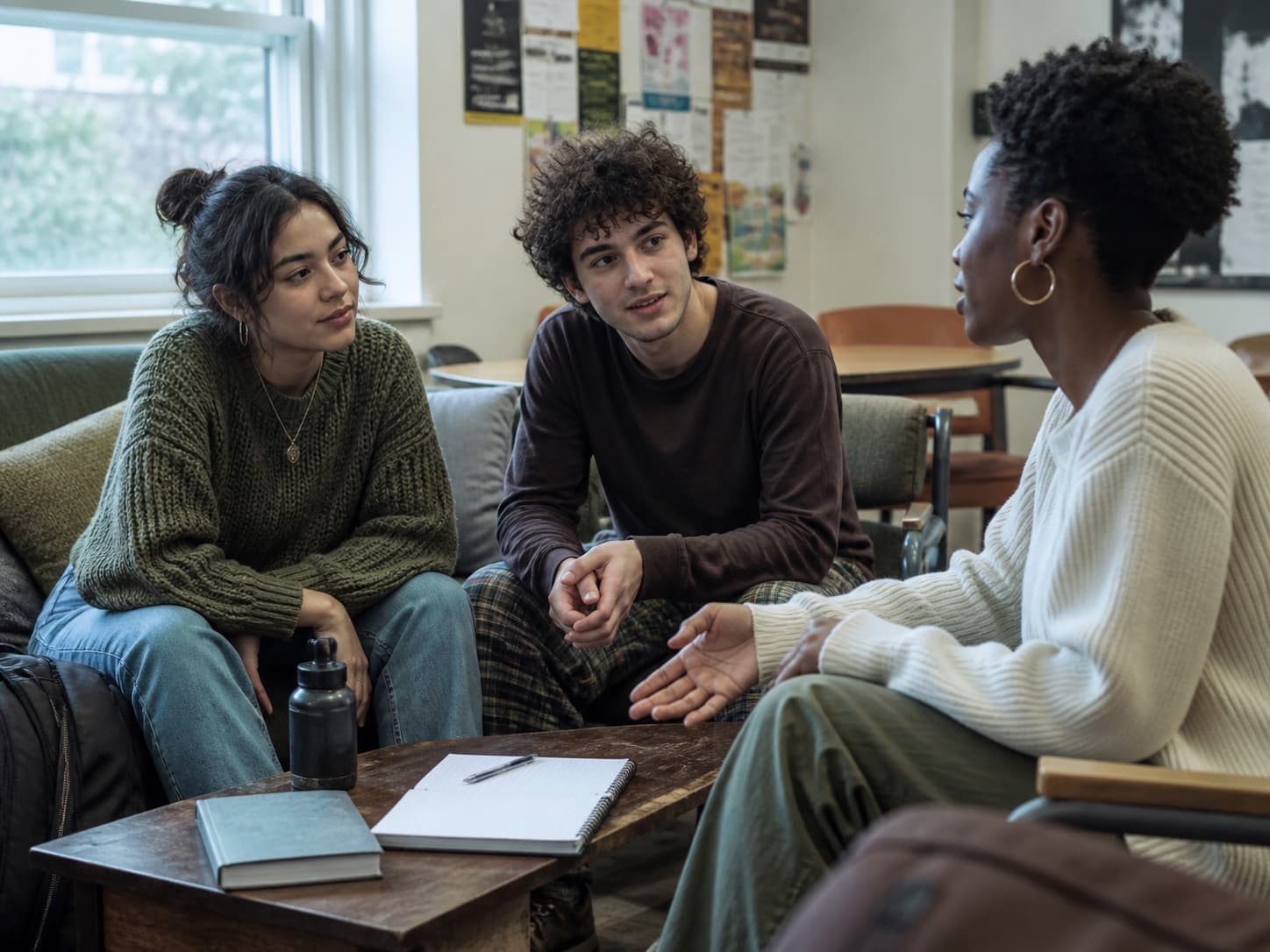College students sharing a candid peer-support conversation in a campus recovery lounge.